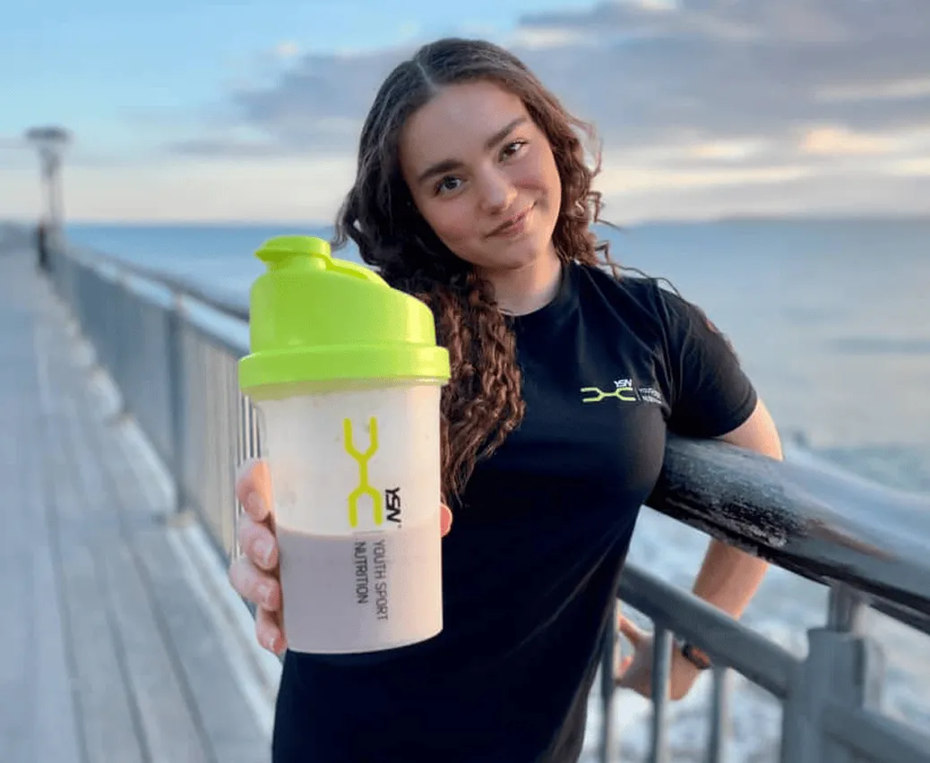 Young athlete holding a YSN shaker by the sea